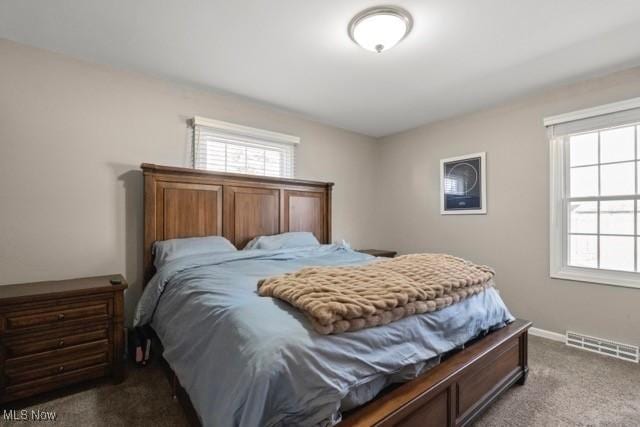 carpeted bedroom featuring multiple windows, baseboards, and visible vents