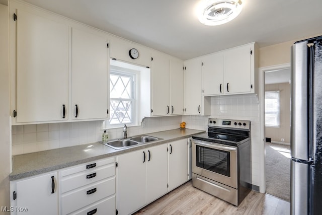 kitchen featuring a healthy amount of sunlight, appliances with stainless steel finishes, light wood-style floors, and a sink