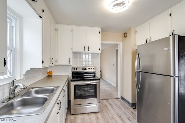 kitchen with tasteful backsplash, white cabinetry, stainless steel appliances, and a sink