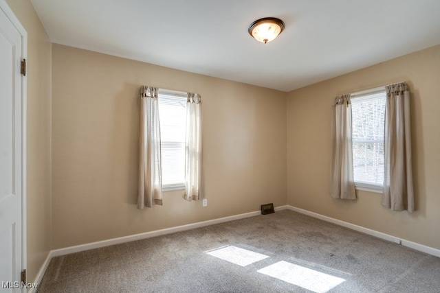 carpeted spare room featuring a wealth of natural light and baseboards