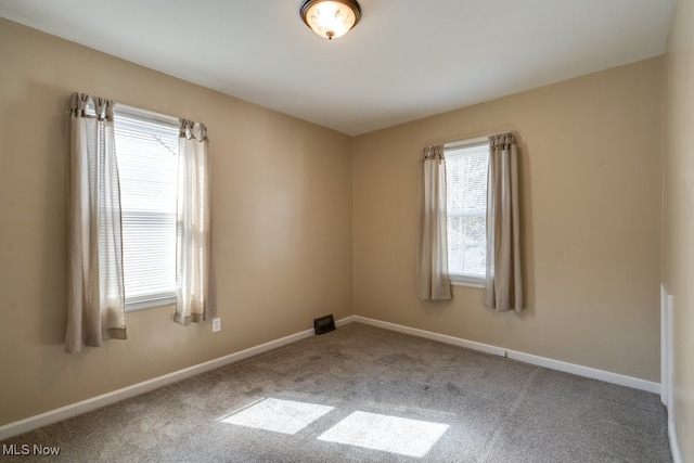 carpeted spare room featuring baseboards