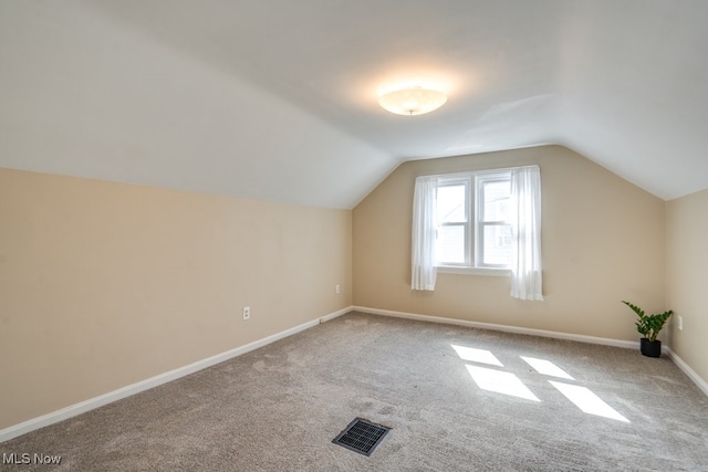 additional living space with visible vents, carpet flooring, lofted ceiling, and baseboards