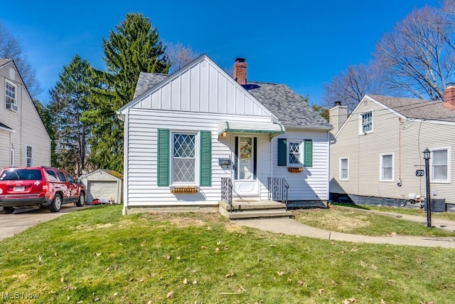 bungalow featuring a front yard, central AC, a shingled roof, a garage, and board and batten siding