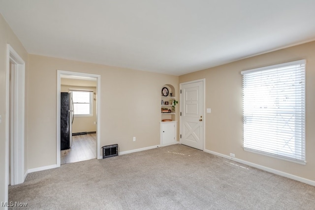 unfurnished room with light carpet, visible vents, and baseboards