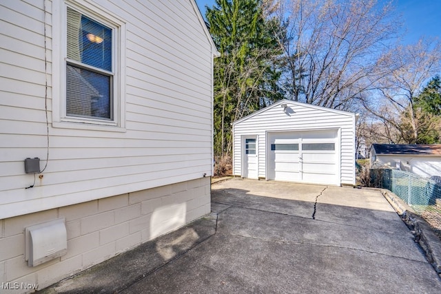 detached garage with concrete driveway and fence