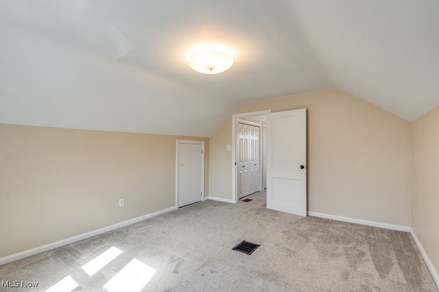 additional living space with visible vents, carpet, baseboards, and vaulted ceiling