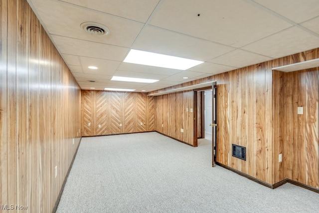 finished basement featuring visible vents, wooden walls, and carpet flooring