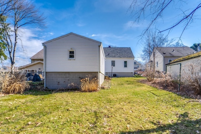 rear view of property featuring a yard and roof with shingles