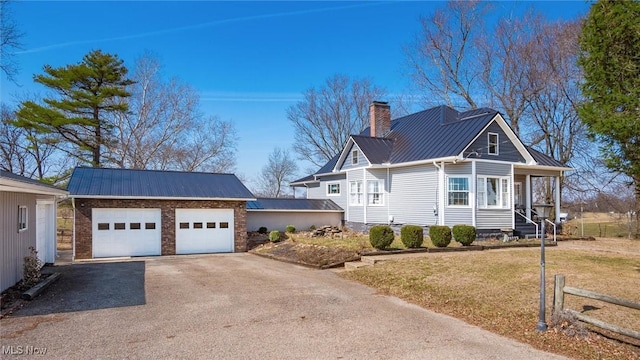 view of home's exterior featuring a lawn, a standing seam roof, aphalt driveway, metal roof, and a chimney