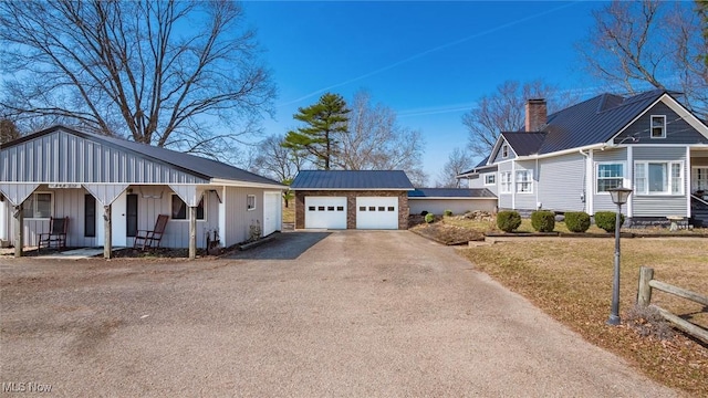 view of front of house featuring a standing seam roof, a porch, an outdoor structure, metal roof, and a chimney