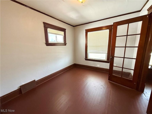 spare room featuring dark wood-style floors, visible vents, baseboards, and ornamental molding