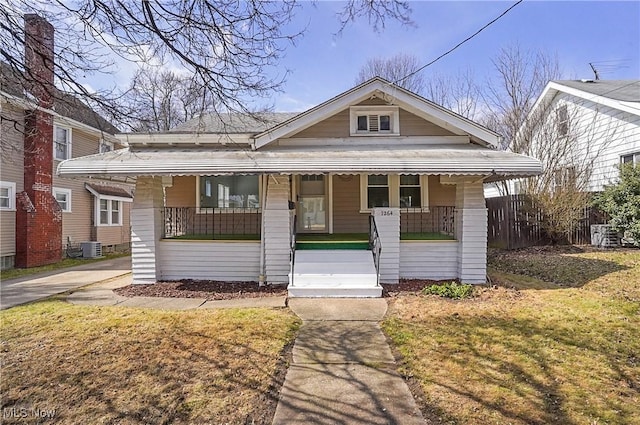 bungalow-style house featuring central air condition unit, covered porch, a front yard, and fence