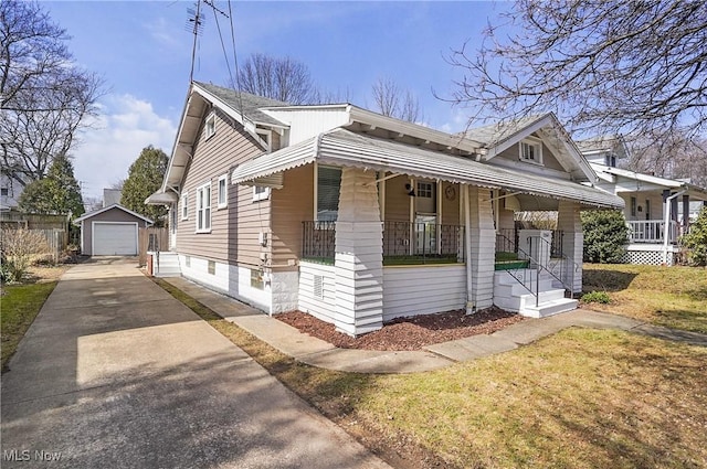 view of front of home featuring a porch, concrete driveway, an outbuilding, and a garage