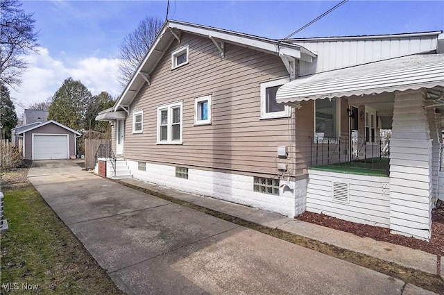 view of side of property featuring a detached garage, an outbuilding, a porch, and concrete driveway