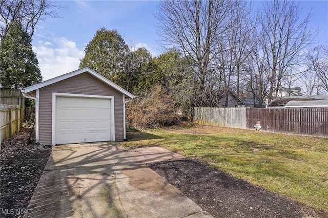 detached garage featuring concrete driveway and fence