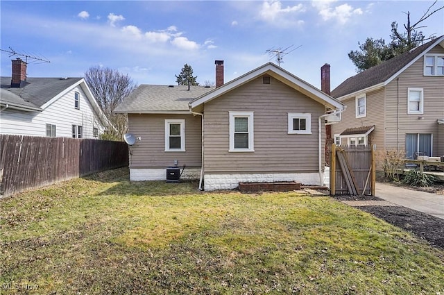 rear view of property with a lawn and fence