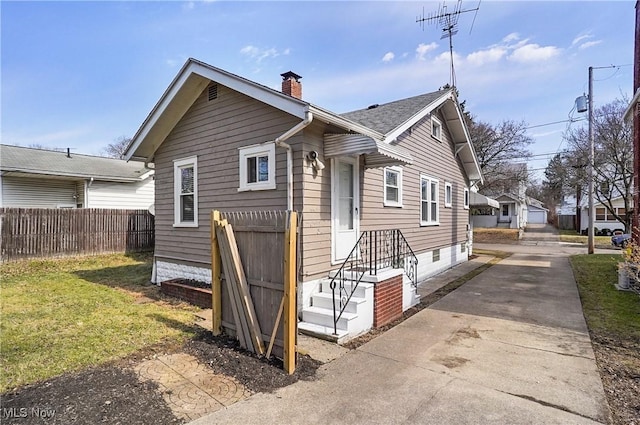 back of property featuring a lawn, a shingled roof, a chimney, and fence