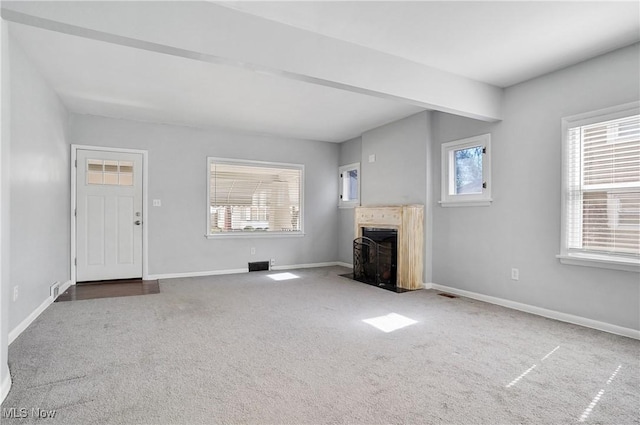 unfurnished living room featuring carpet flooring, a fireplace with flush hearth, and plenty of natural light