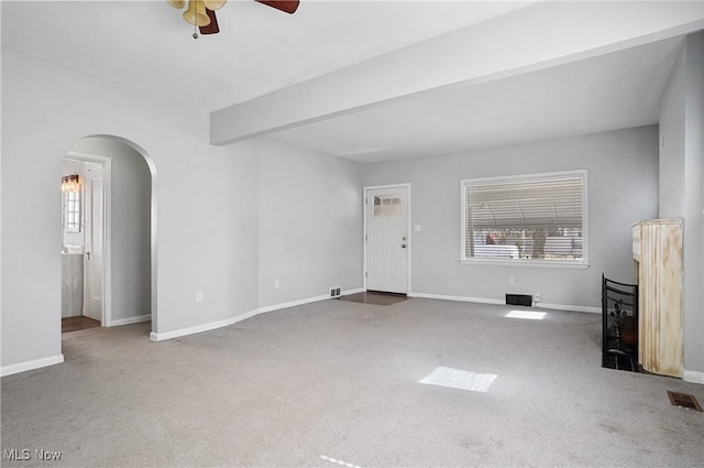 unfurnished living room featuring visible vents, beam ceiling, arched walkways, carpet, and baseboards