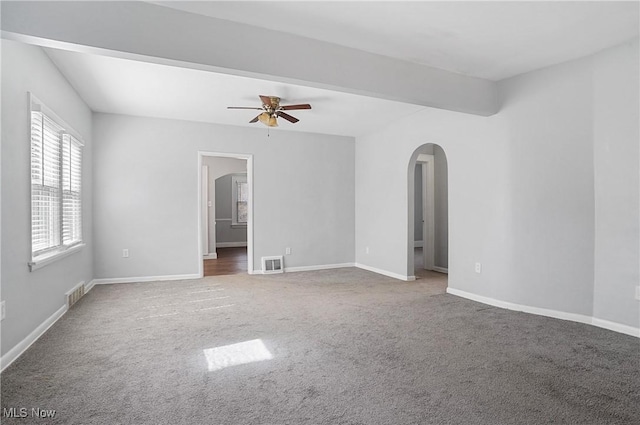 spare room featuring arched walkways, visible vents, baseboards, and carpet floors