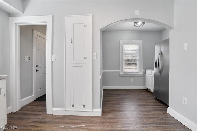 kitchen with dark wood-type flooring, light countertops, stainless steel refrigerator with ice dispenser, arched walkways, and white cabinets