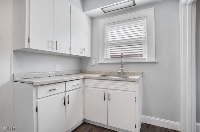 kitchen featuring visible vents, a sink, white cabinetry, light countertops, and baseboards