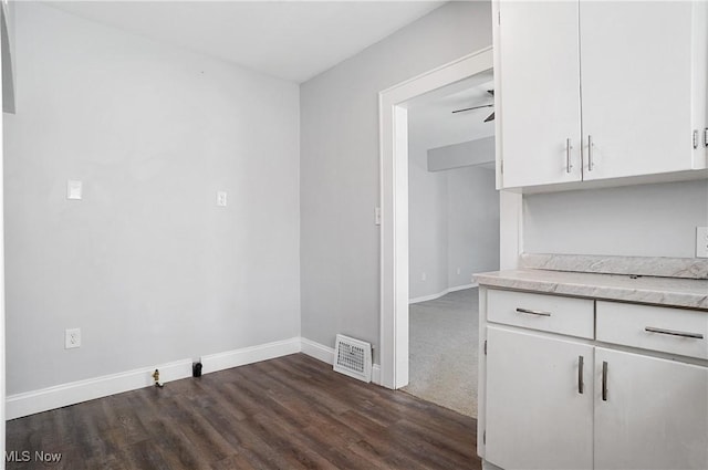 kitchen featuring visible vents, dark wood-type flooring, baseboards, white cabinetry, and a ceiling fan