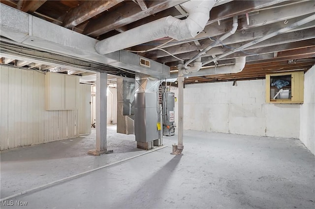 unfinished basement with water heater, visible vents, and heating unit