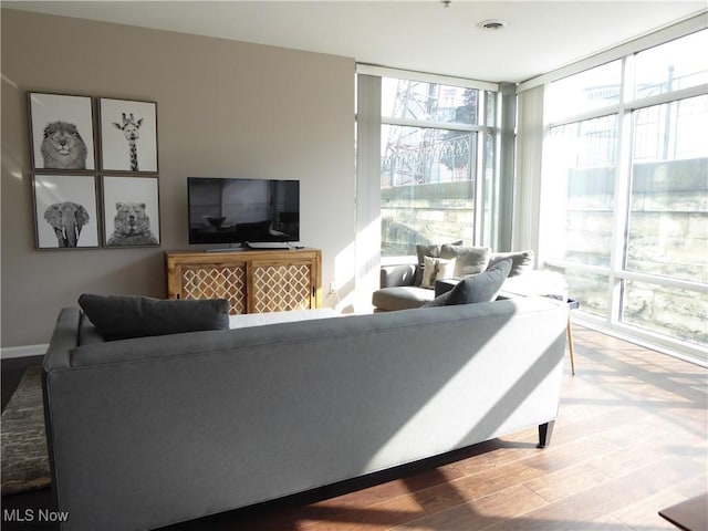 living room featuring floor to ceiling windows, wood finished floors, visible vents, and baseboards