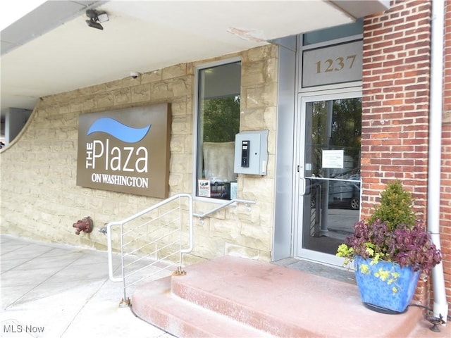 entrance to property featuring electric panel and brick siding