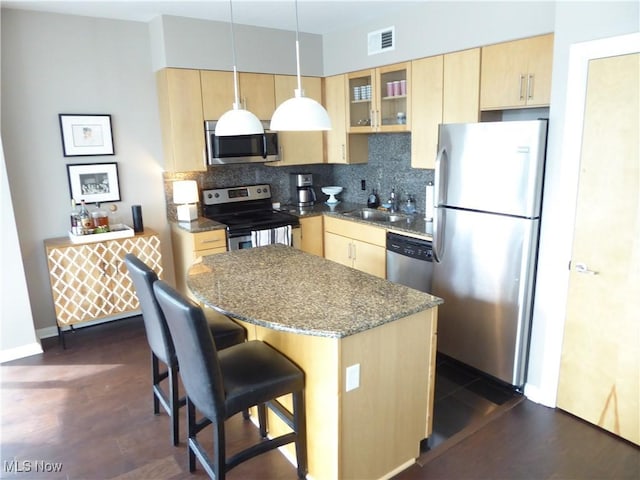 kitchen with a sink, visible vents, appliances with stainless steel finishes, and light brown cabinetry