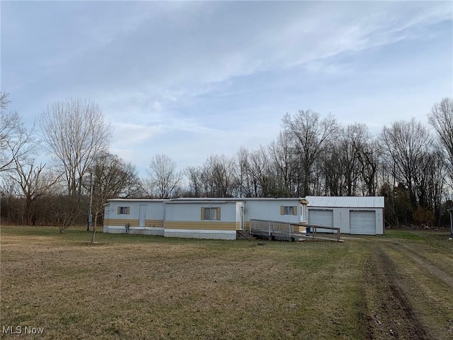 manufactured / mobile home featuring a garage, an outdoor structure, and a front lawn