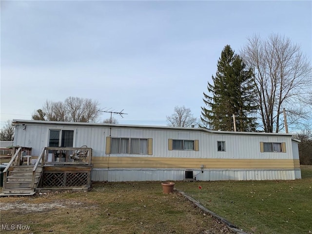 rear view of property featuring a wooden deck, a yard, and central AC