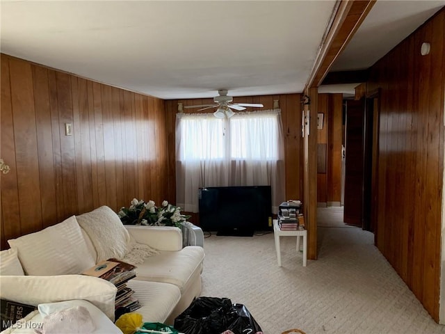 living room with light carpet, wood walls, and a ceiling fan