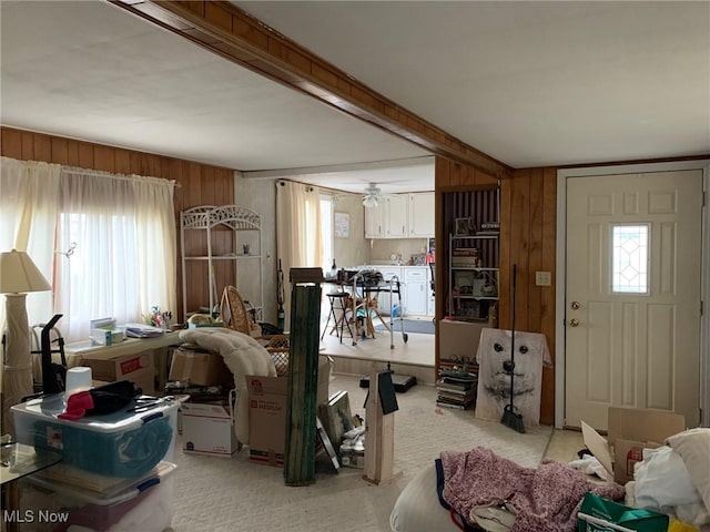 living room featuring plenty of natural light, wood walls, and beamed ceiling