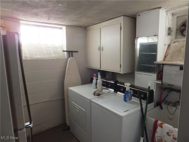 washroom featuring cabinet space, a textured ceiling, independent washer and dryer, and concrete block wall