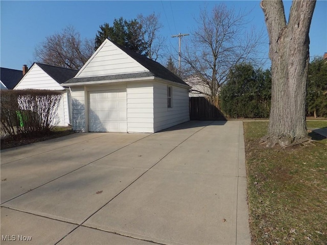 garage with concrete driveway and fence