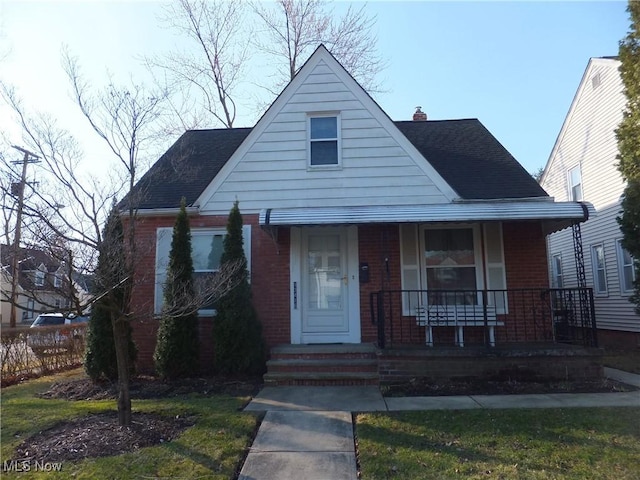 bungalow-style house with brick siding, a porch, a chimney, and roof with shingles