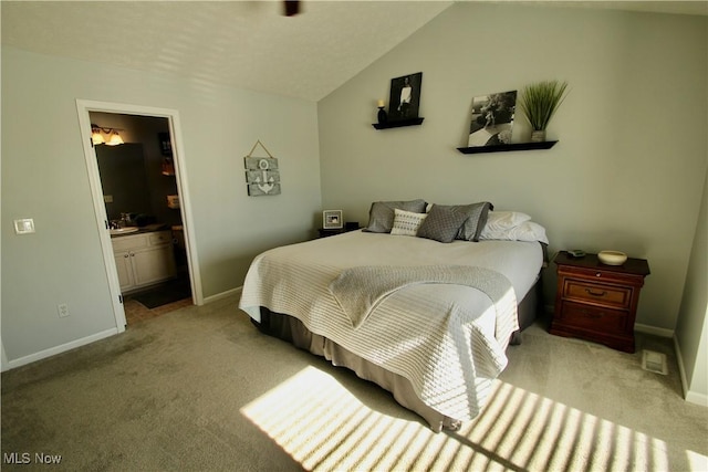 carpeted bedroom featuring lofted ceiling, baseboards, and connected bathroom