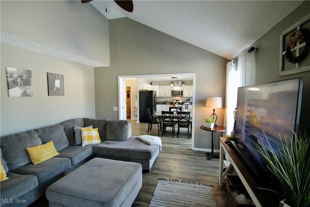 living room with baseboards, a ceiling fan, dark wood-style flooring, and vaulted ceiling