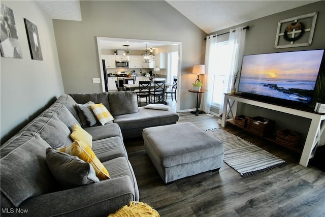 living room featuring dark wood-type flooring, a notable chandelier, baseboards, and vaulted ceiling