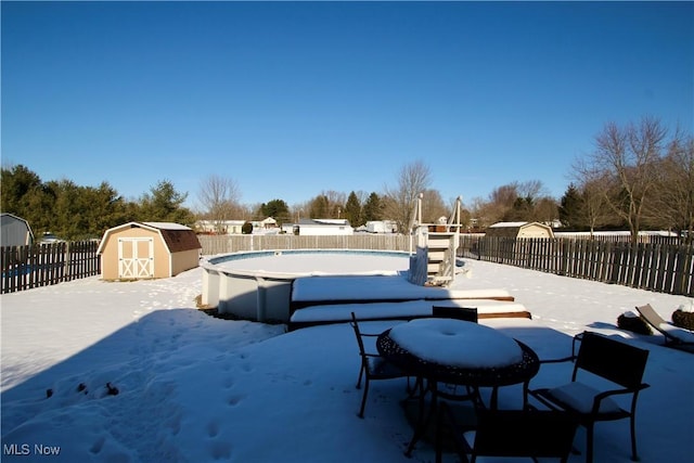 exterior space featuring a fenced in pool, outdoor dining area, a fenced backyard, an outdoor structure, and a storage unit