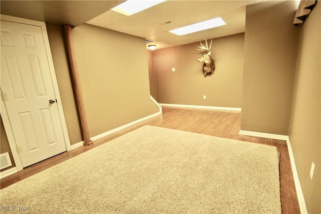 finished below grade area with wood finished floors, baseboards, and a drop ceiling