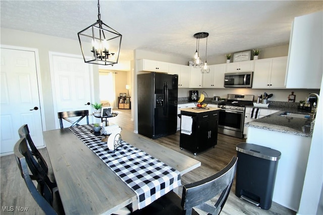 kitchen with a sink, a center island, white cabinetry, stainless steel appliances, and an inviting chandelier