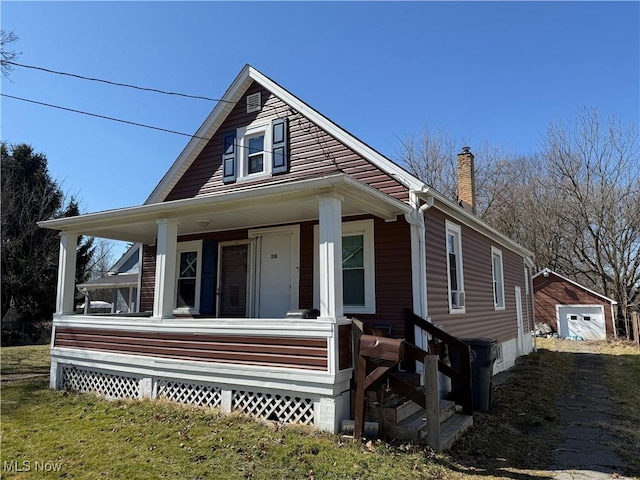 view of front of house featuring a porch, a garage, and a chimney