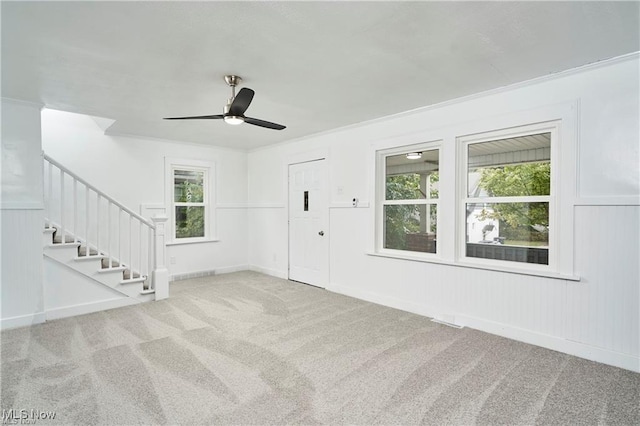 carpeted entrance foyer featuring stairway, plenty of natural light, a ceiling fan, and visible vents