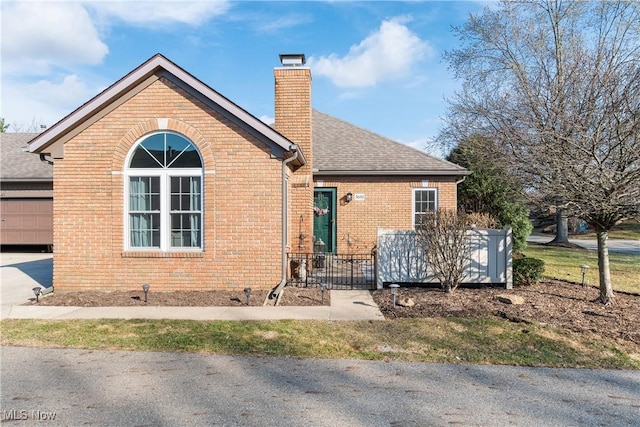 exterior space featuring brick siding, a chimney, and a shingled roof