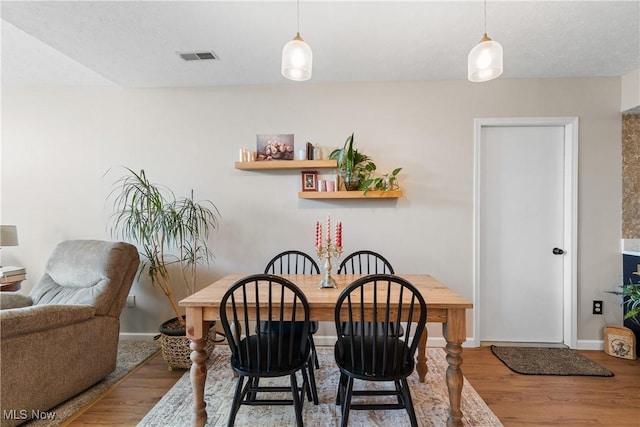 dining area featuring visible vents, baseboards, and wood finished floors