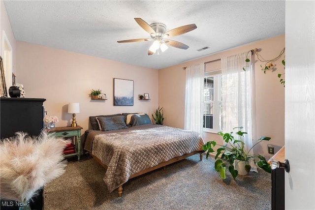 carpeted bedroom with visible vents, a textured ceiling, and a ceiling fan