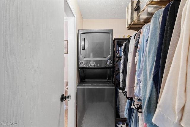 laundry room with a textured ceiling, laundry area, and stacked washer / dryer